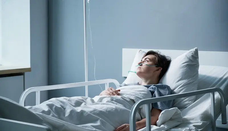 Hospitalized patient in a bed with oxygen support, resting in a quiet and clean hospital environment.