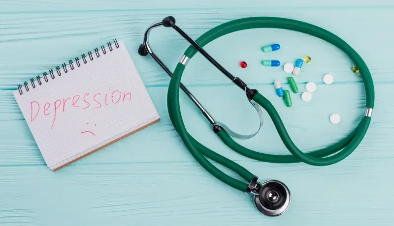 A stethoscope, pills, and a notebook with the word "Depression" written on it, symbolizing the role of medication and therapy in treating depression.