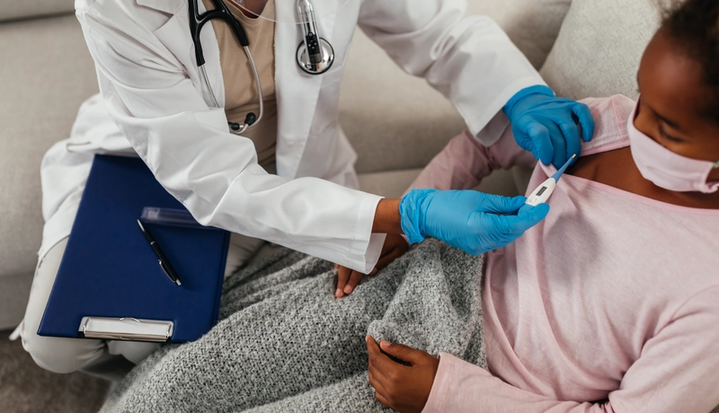 A doctor checking the temperature of a child during a pneumonia examination.